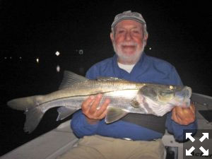 Night snook fishing is usually very good during winter unless water temperatures drop too low. Martin Marlowe, from NY, with a snook caught and released on a Grassett Snook Minnow fly while fishing dock lights at night in the ICW with Capt. Rick Grassett in a previous February.